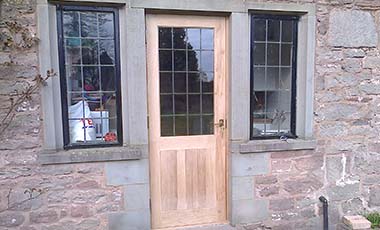 Fitted bespoke oak door with leaded glass panes with a leaded glass window either side
