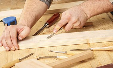 woodworker using small chisel on piece of wood