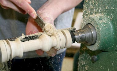 wood lathe spinning wood with man carving out patten with tool