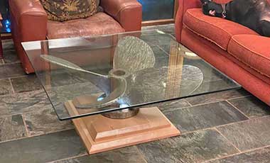 glass top coffee table made from a ship propeller upon a bespoke wood plinth